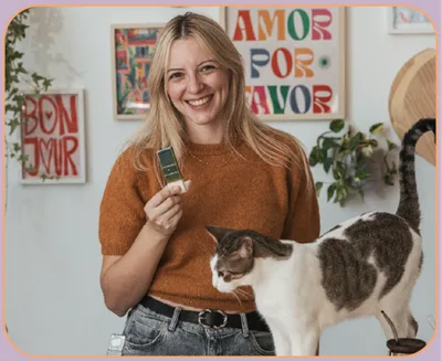 Nati sonriendo en su taller, con una herramienta de cerámica en la mano y su gato al lado